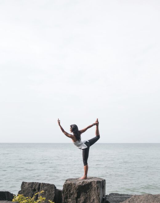 Postura de equilibrio sobre una roca frente al mar