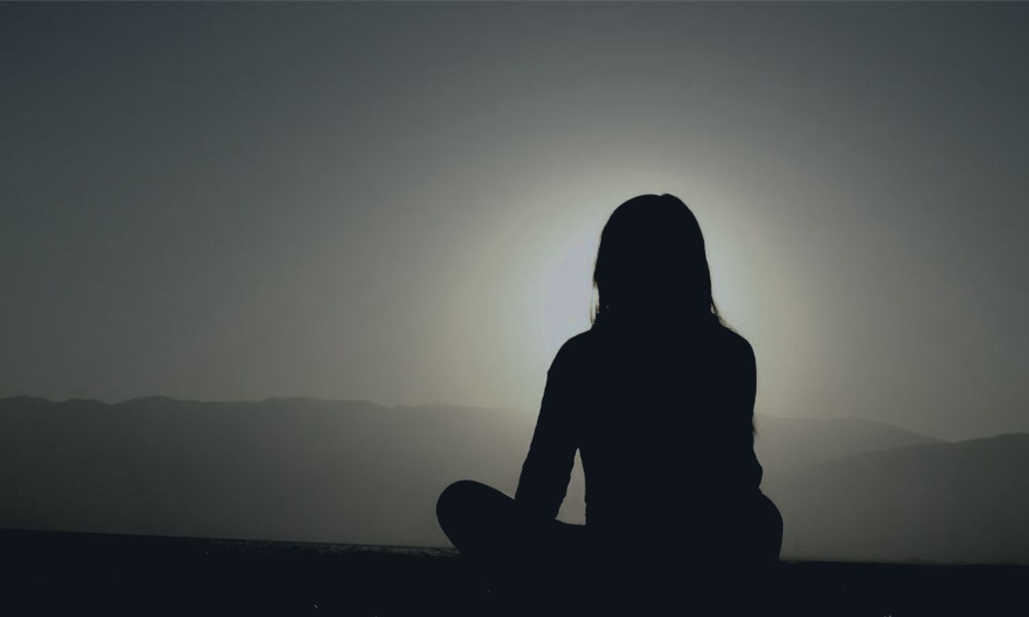 Silueta en meditación durante el atardecer